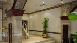 A grand staircase with marble steps, a potted plant, and a chair. - Philippe Luxor Hotel (Luxor)