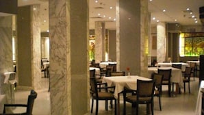 A restaurant with marble columns, round tables, and chairs. - Philippe Luxor Hotel (Luxor)