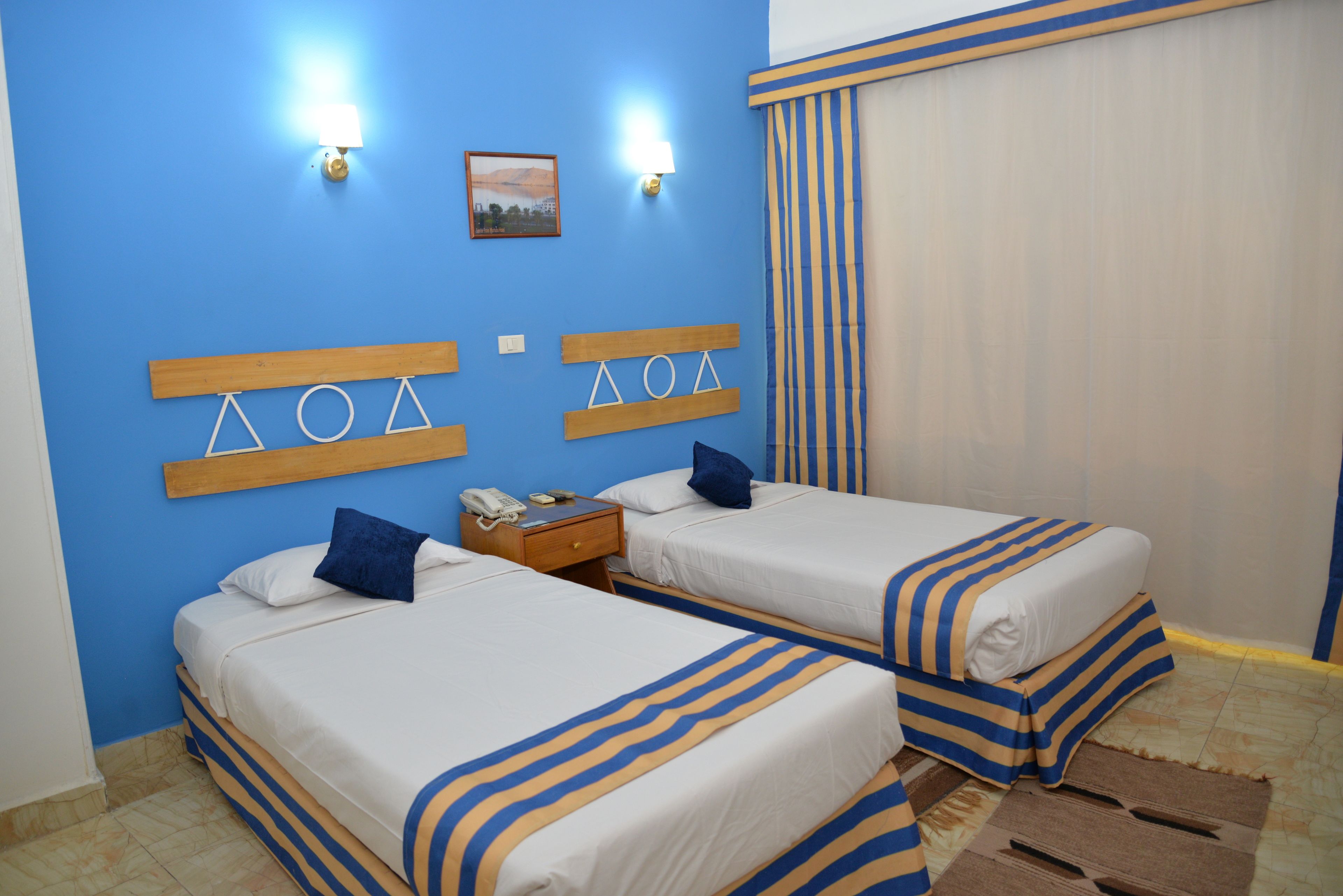 Une chambre d’hôtel avec deux lits, une table de chevet et une lampe fixée au mur.