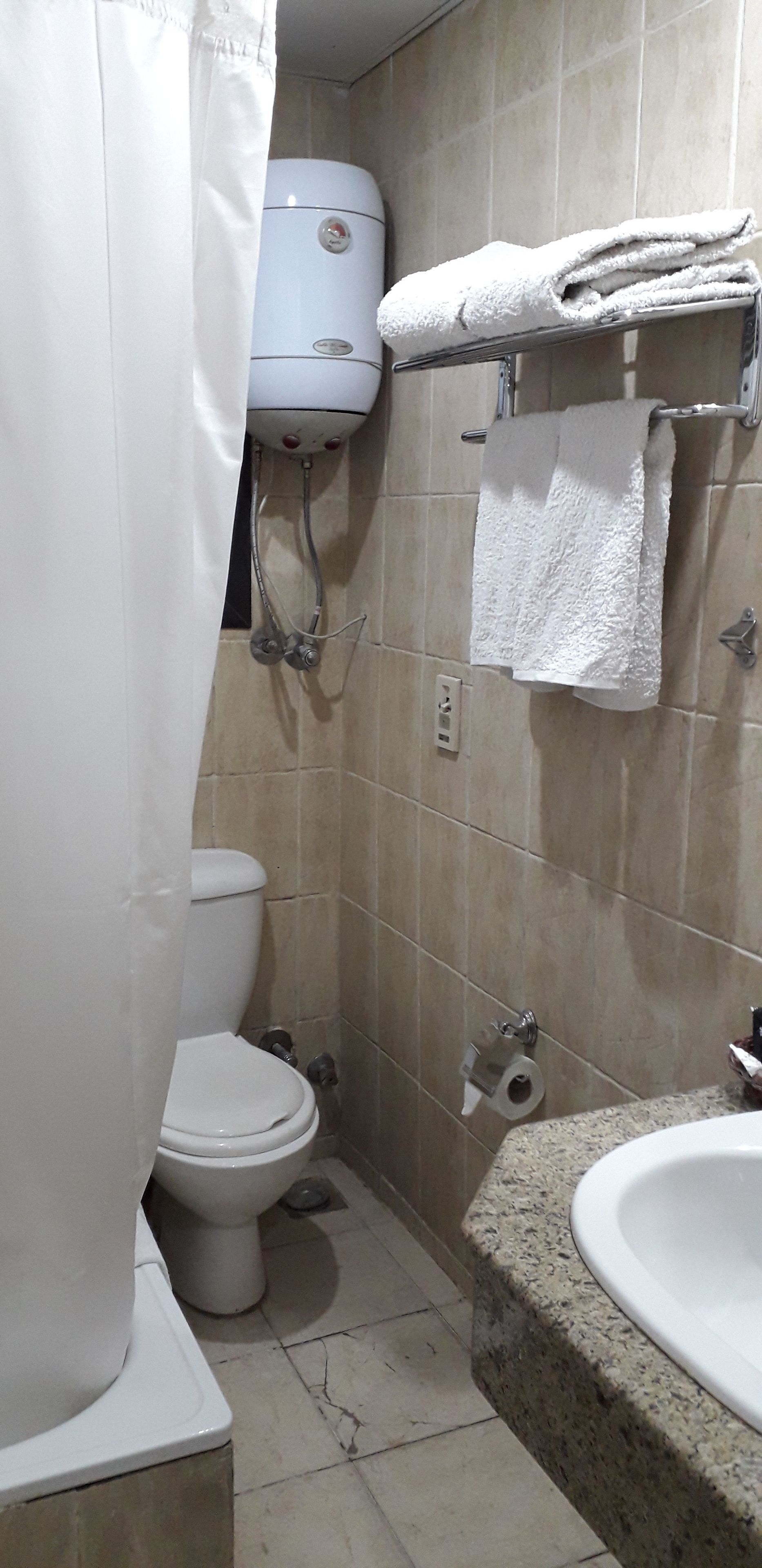 A bathroom with a toilet, shower, and sink.