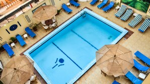 A swimming pool with blue water, surrounded by lounge chairs and umbrellas. - Marhaba Hotel Aswan (Aswan)