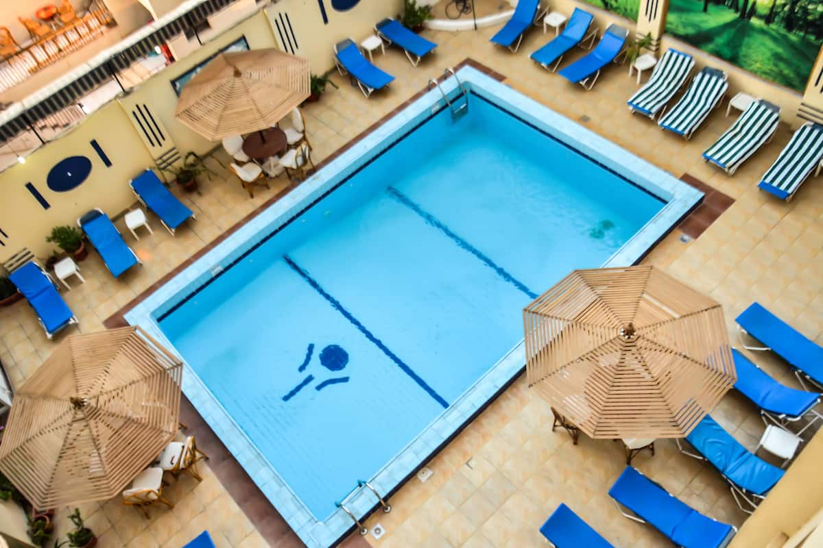 A swimming pool with blue water, surrounded by lounge chairs and umbrellas.