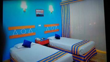 Habitación de hotel con dos camas, una mesita de noche, un teléfono y una ventana con cortinas.