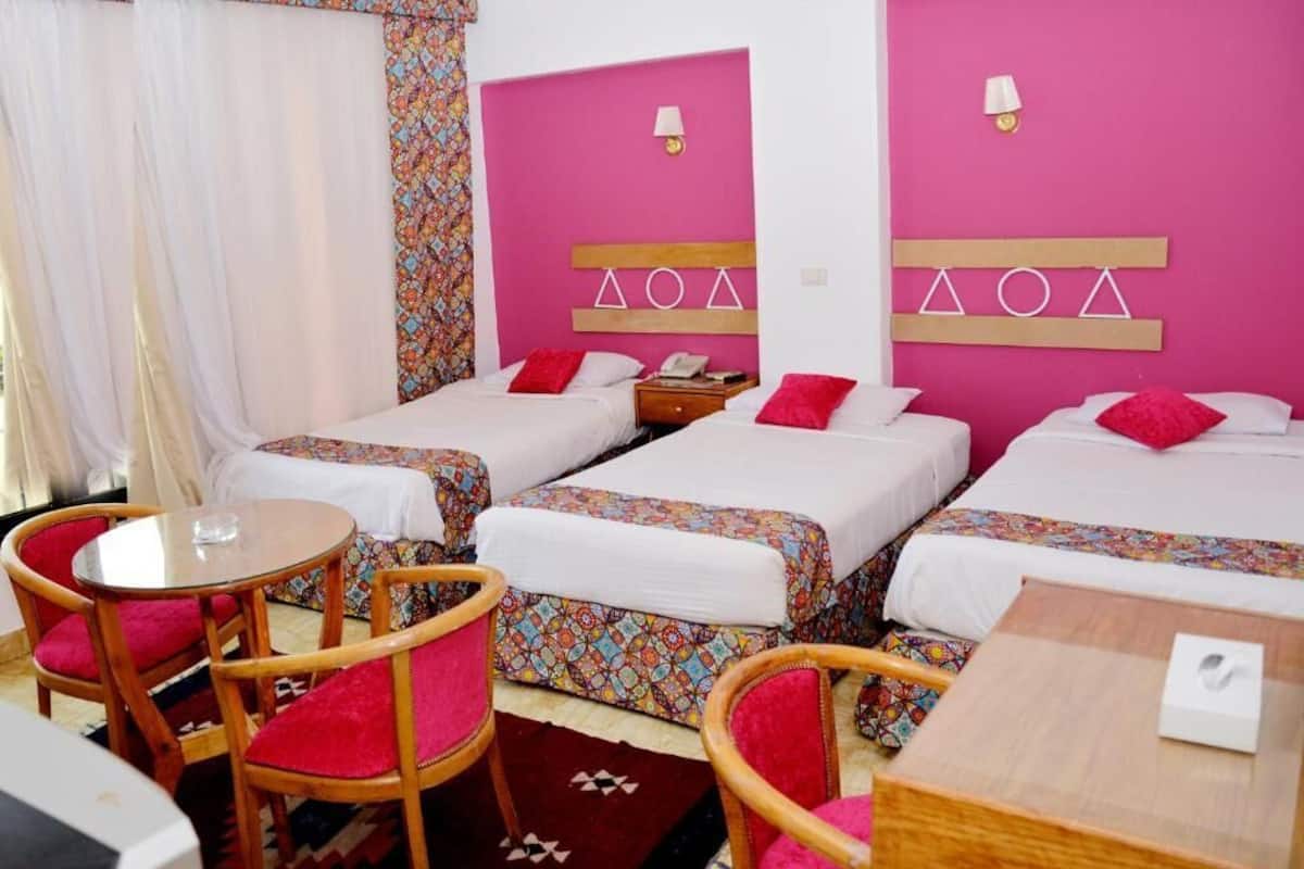 A hotel room with two beds, a small table, and two chairs.
