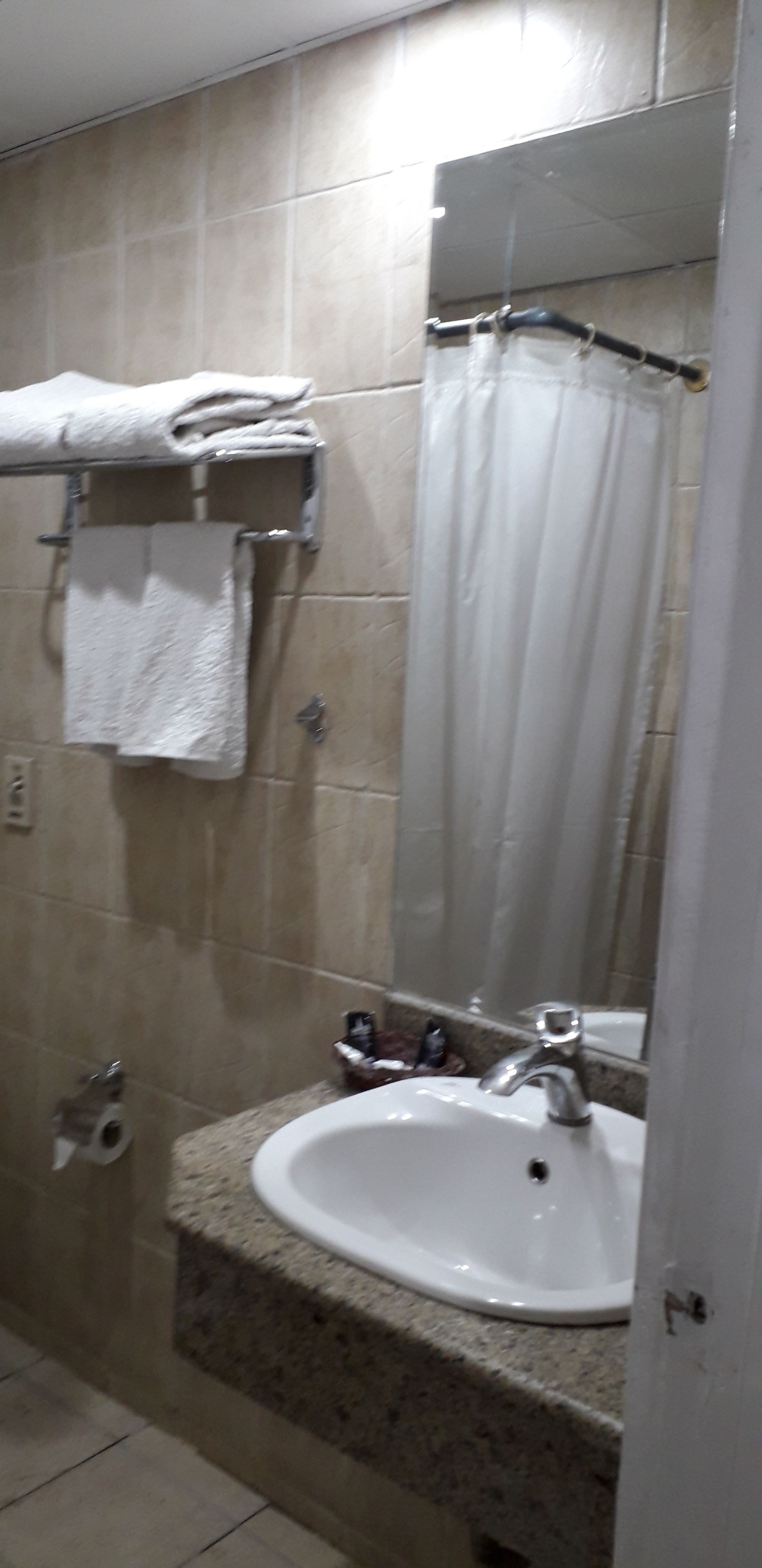 Baño con lavamanos, espejo y perchero para toallas.