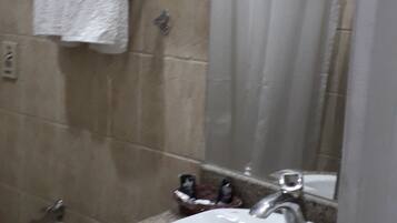 Baño con lavamanos, espejo y perchero para toallas.