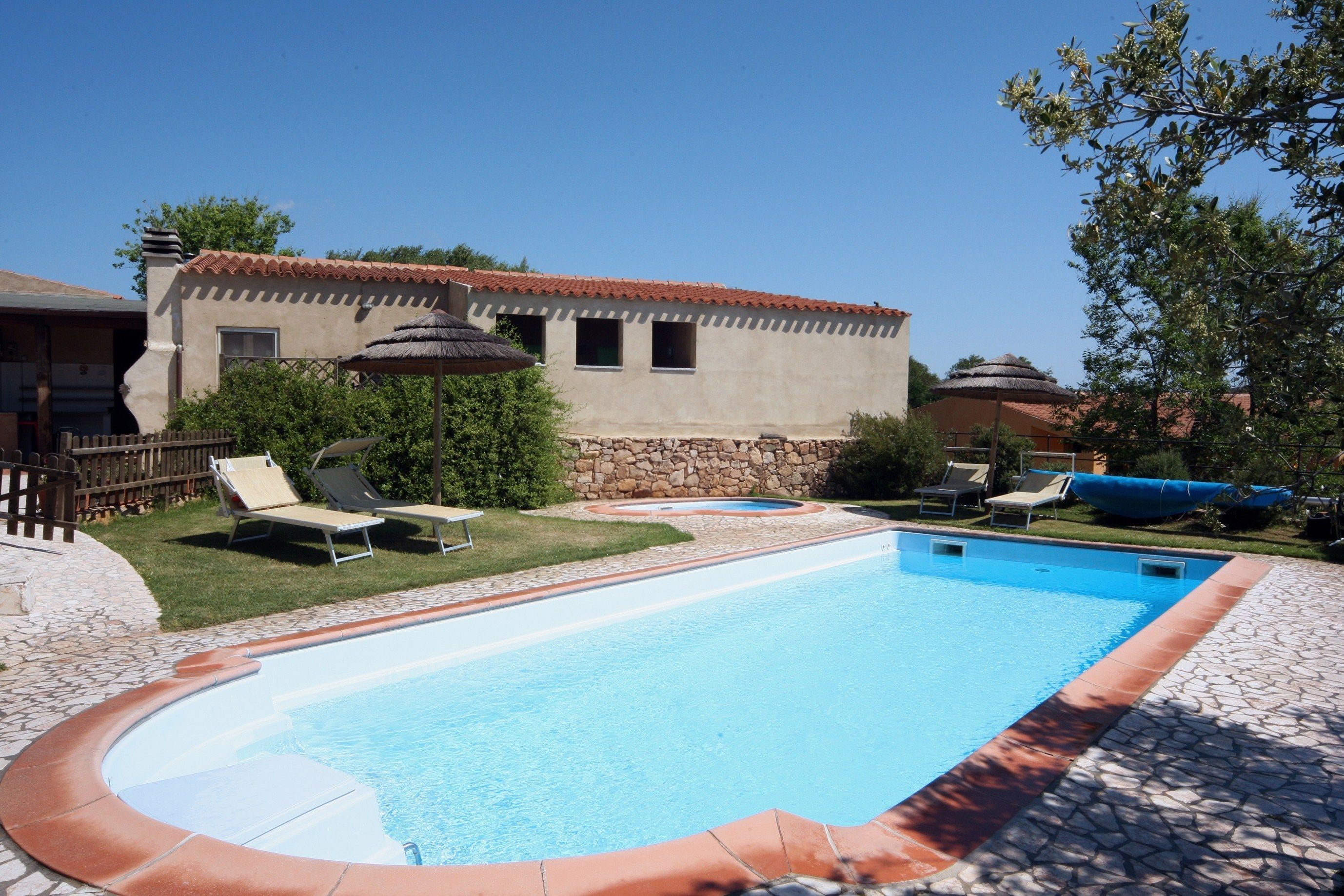 A swimming pool with lounge chairs and a stone wall.
