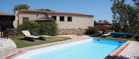 Una piscina con sillones de descanso y una pared de piedra.