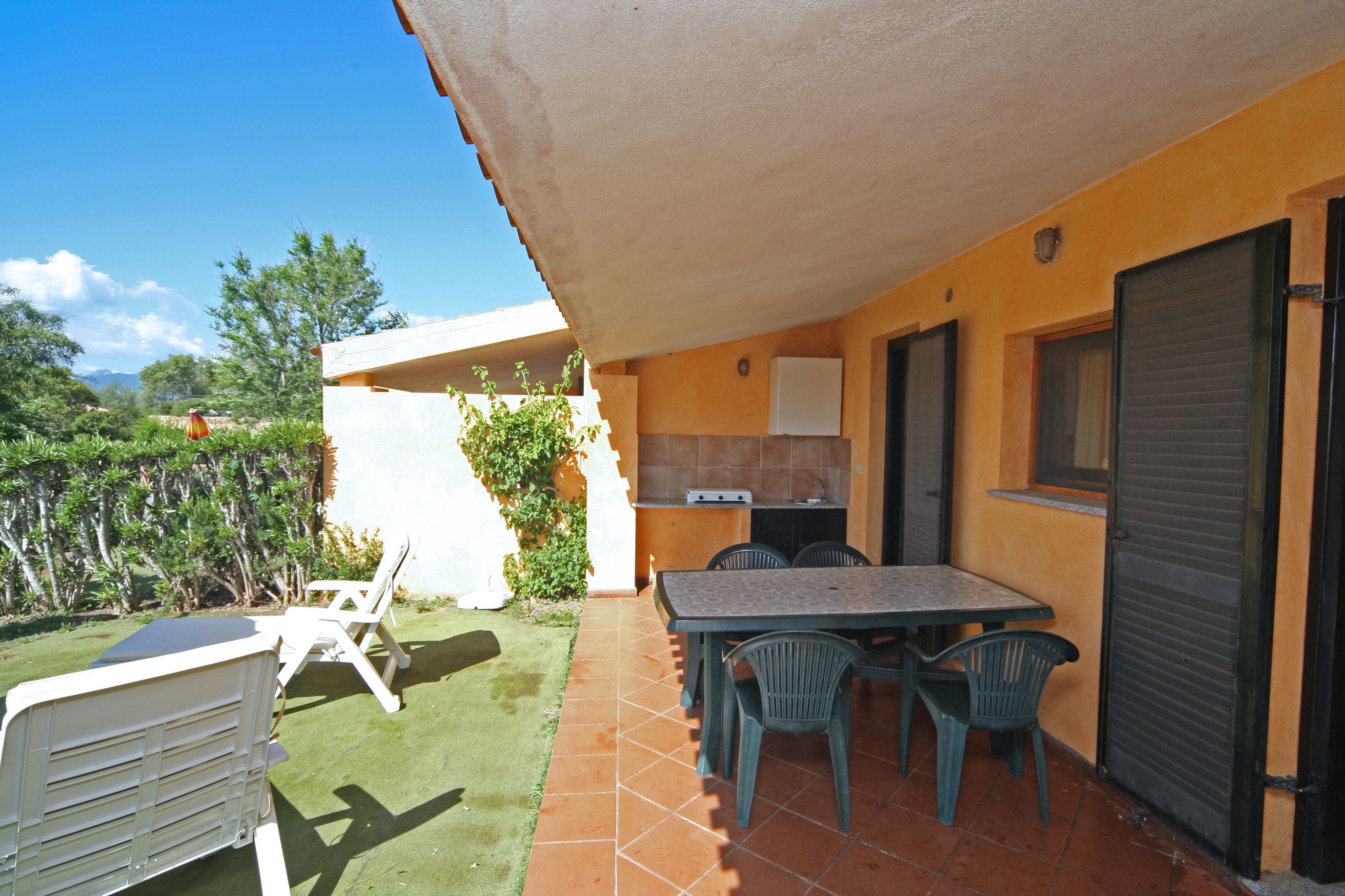 A patio area with a table and chairs, a small kitchen area, and a covered seating area.