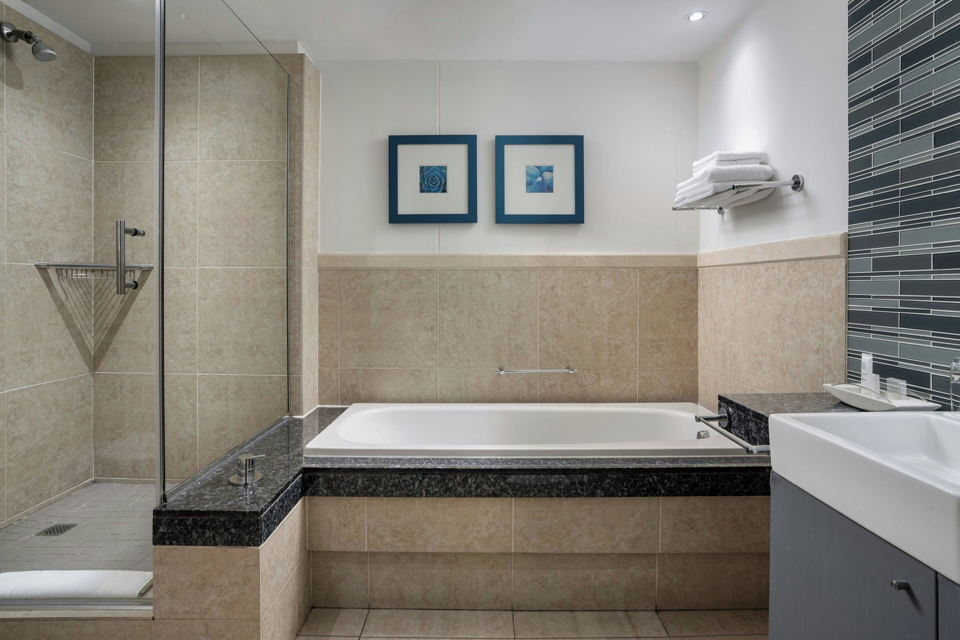 A modern bathroom with a bathtub, shower, and a towel rack.