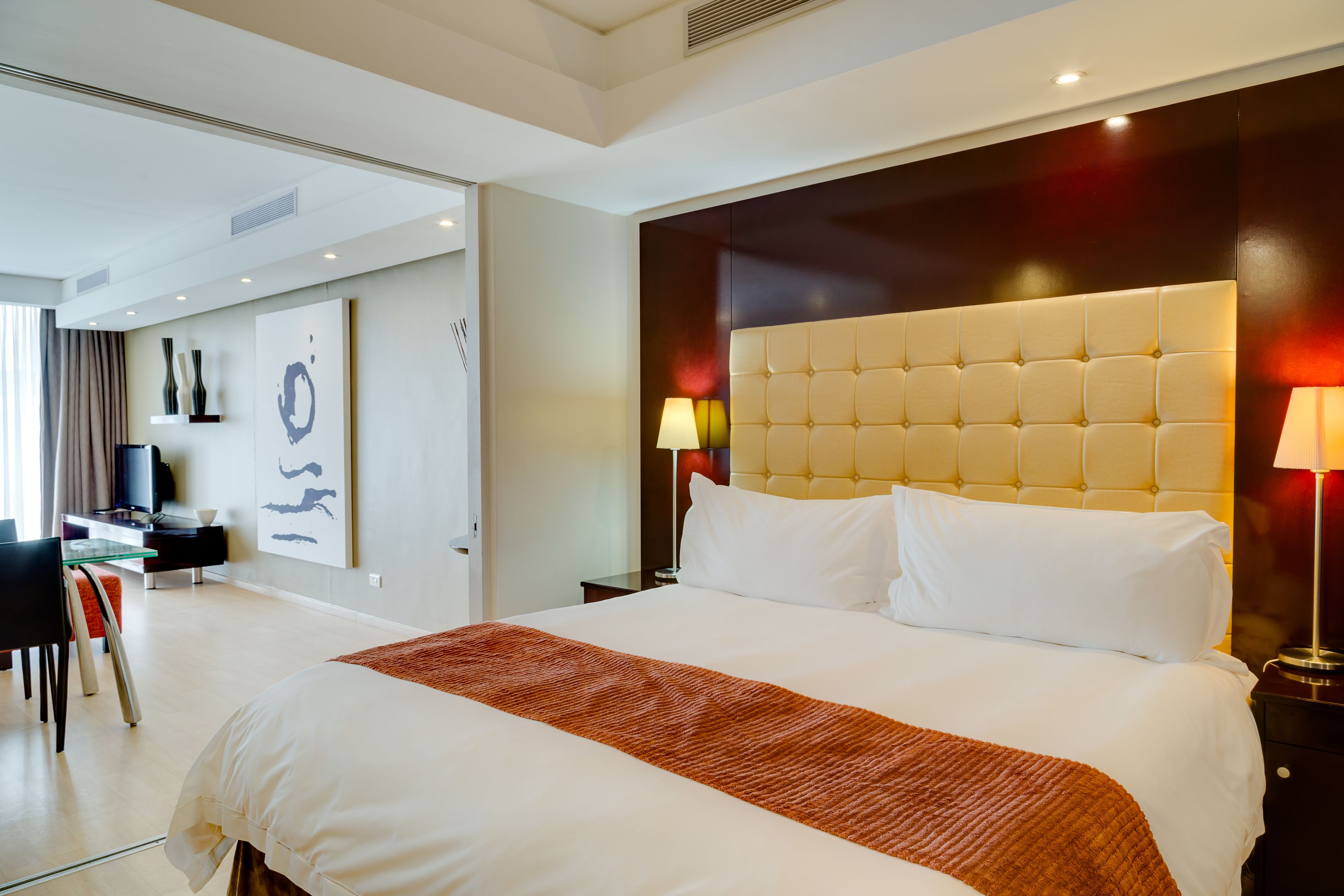 Une chambre d’hôtel avec un grand lit, un bureau avec une chaise, une télévision et des œuvres d’art accrochées au mur.