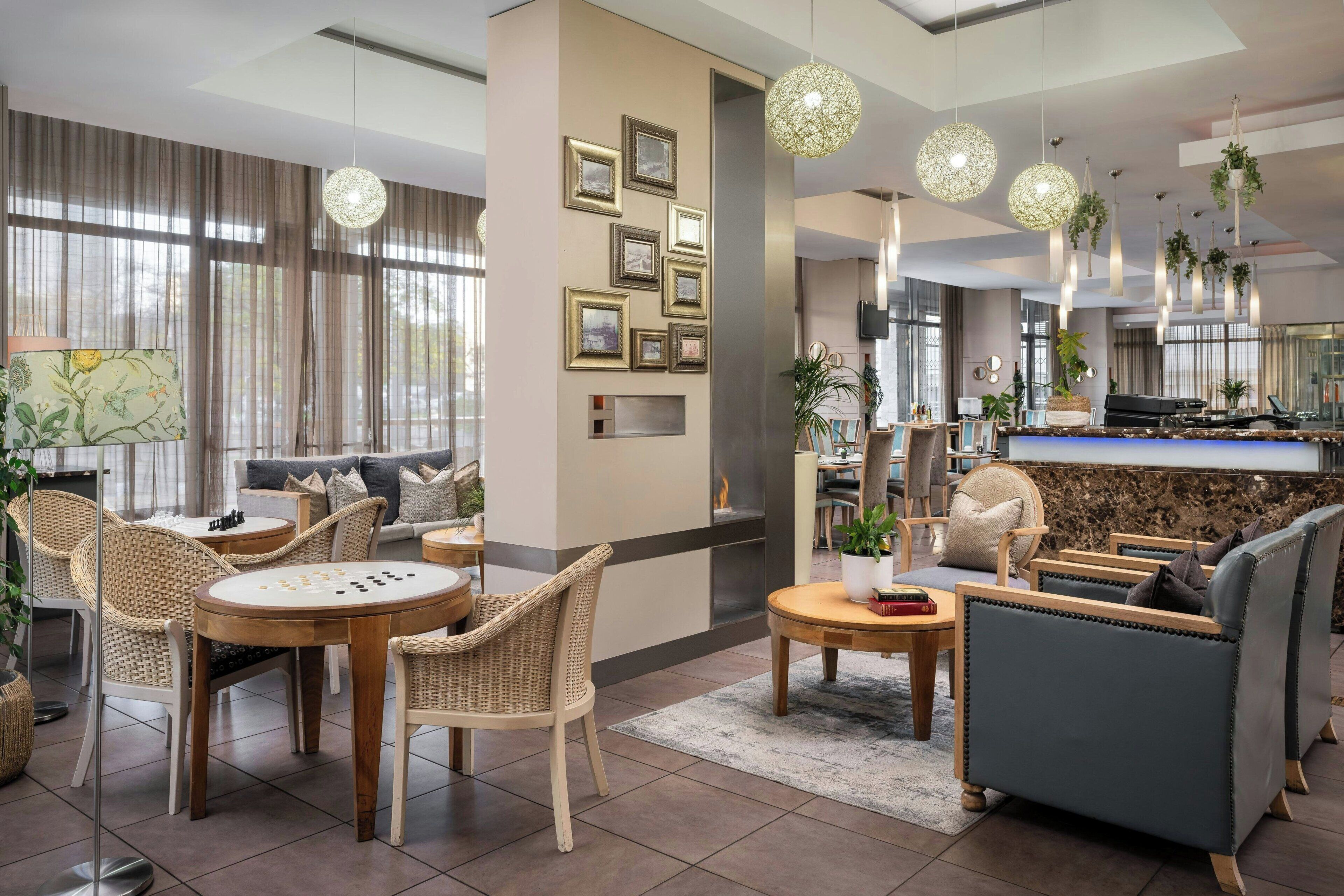 Un moderno vestíbulo de hotel con muebles de mimbre, una recepción de mármol e iluminación colgante.