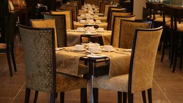 Une longue table à manger, entourée de chaises, préparée pour un repas.