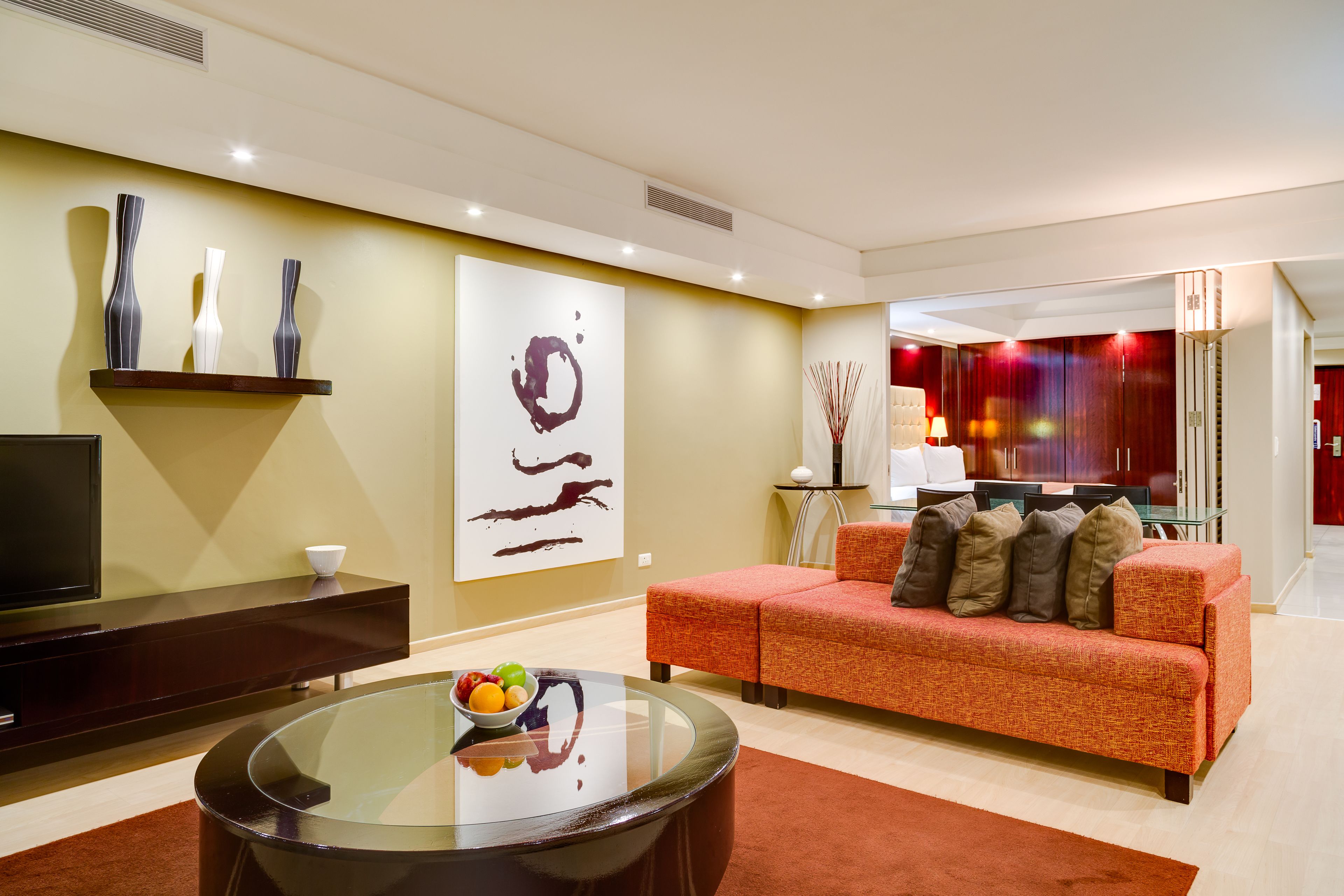 Een moderne woonkamer met een bank, een glazen salontafel en een flatscreen televisie.