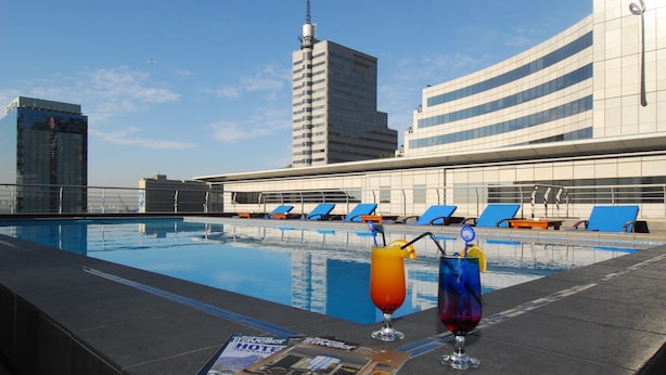 A pool area with lounge chairs and two drinks on a magazine.