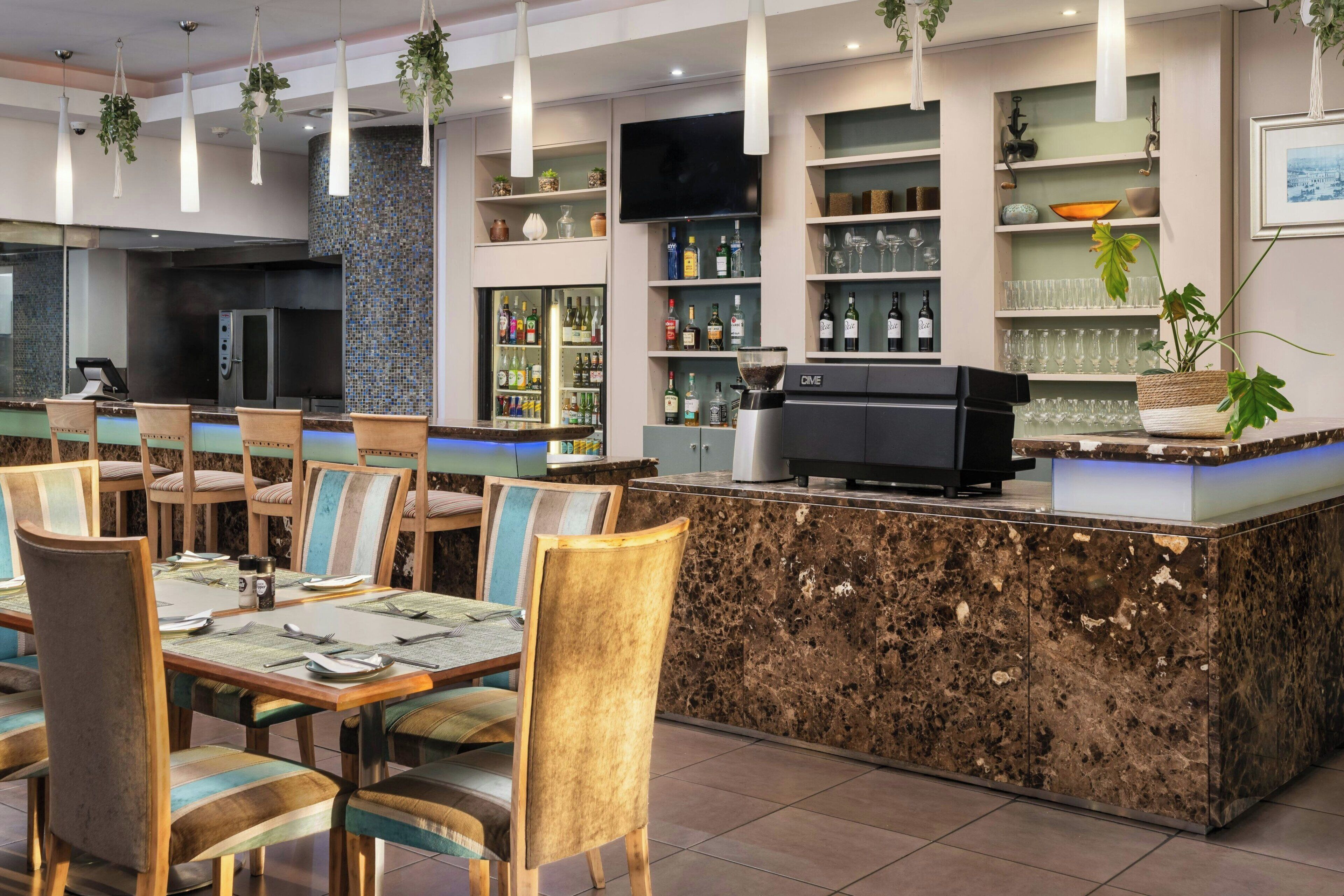 Un restaurante con barra, mesas y una televisión.