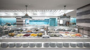 Een buffetopstelling met diverse gerechten en gestapelde borden.