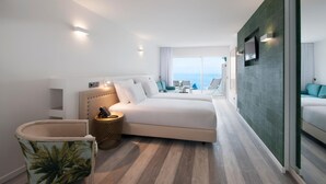 Een moderne hotelkamer met een groot bed, een zithoekje en uitzicht op zee.