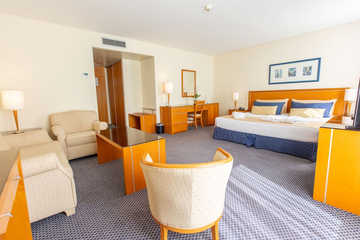 Une chambre d’hôtel comprenant un lit, un bureau, une chaise, une commode et un miroir.