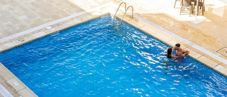 Una piscina al aire libre, tumbonas