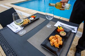 Une table à manger avec deux assiettes de nourriture, deux verres de vin et une bouteille de vin dont on verse le contenu.