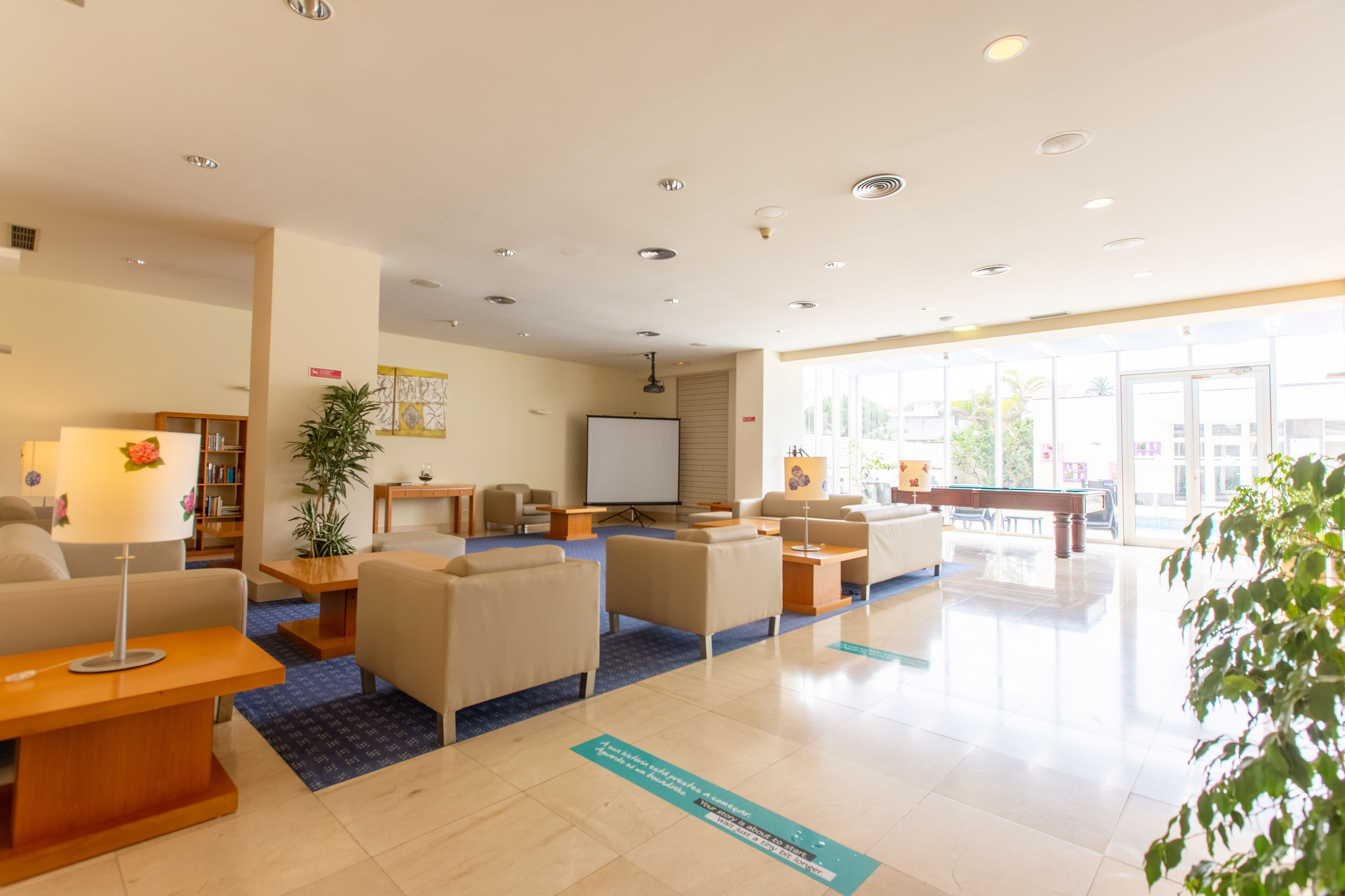 Una hall moderna con reception, area relax e un'ampia finestra che lascia entrare molta luce naturale.