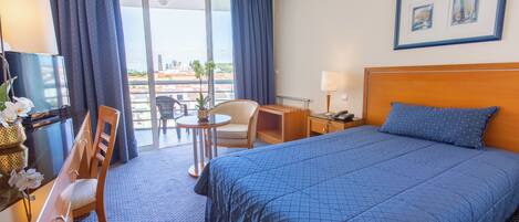 Hotelkamer met een groot bed, een bureau, een stoel, een kleine tafel en een balkon met uitzicht.