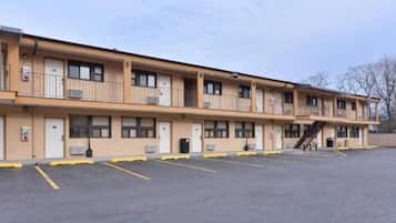 A multi-story motel with a parking lot in front.