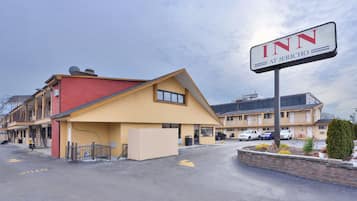 A motel with a red and yellow exterior, a signboard for 'INN AT JERICHO', and a parking lot with cars.