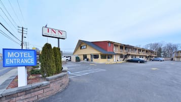 A motel entrance with a sign for the Inn at Jericho, a parking lot, and a building with multiple balconies.