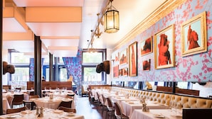A restaurant with multiple dining tables, a long bench seating area, and framed artwork on the walls. - 21c Museum Hotel Louisville (Louisville)