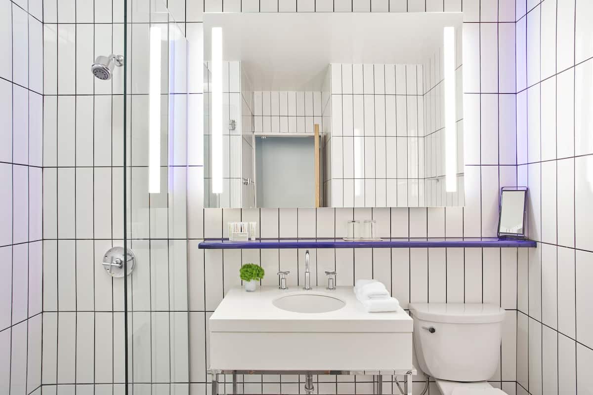 A modern bathroom with a white sink, mirror, and toilet.