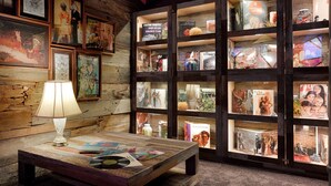 A cozy room with wooden walls, a table with a lamp, and shelves displaying books and decorative items. - 21c Museum Hotel Louisville (Louisville)