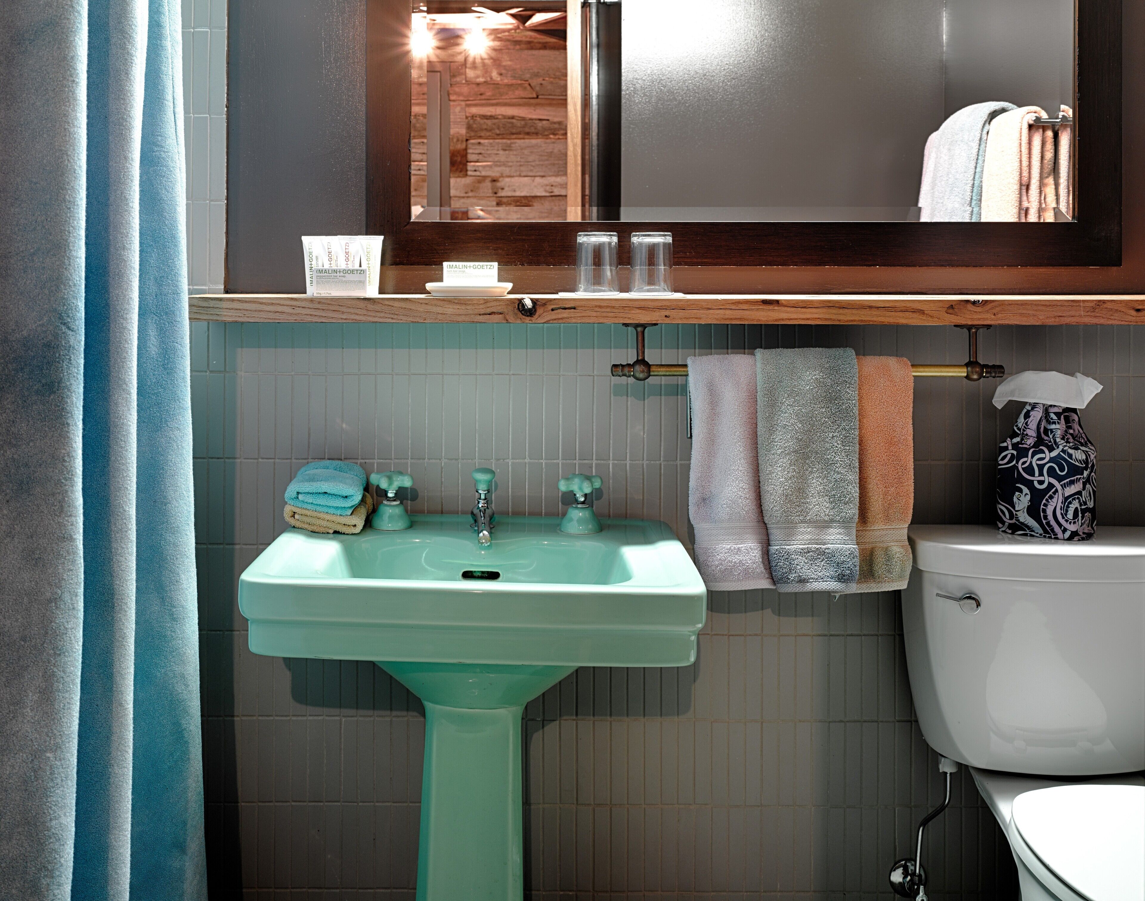 A bathroom with a green sink, a white toilet, and a mirror above the sink.