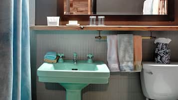 A bathroom with a green sink, a white toilet, and a mirror above the sink.