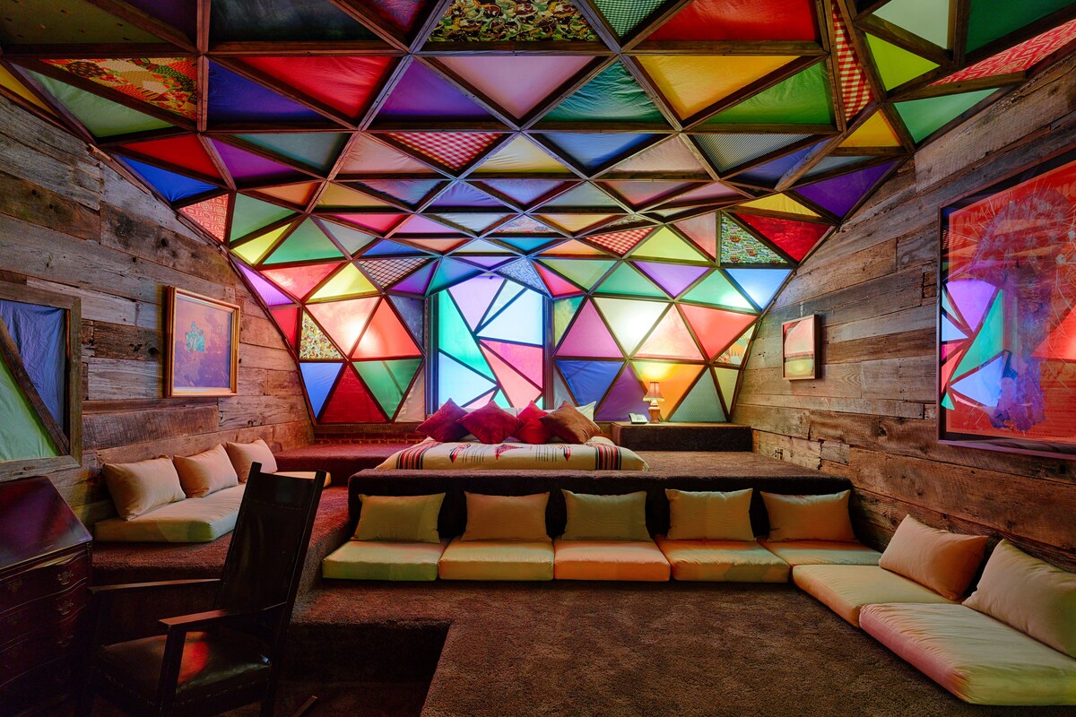 A cozy room with a geometric-patterned ceiling, a sofa, and a chair.