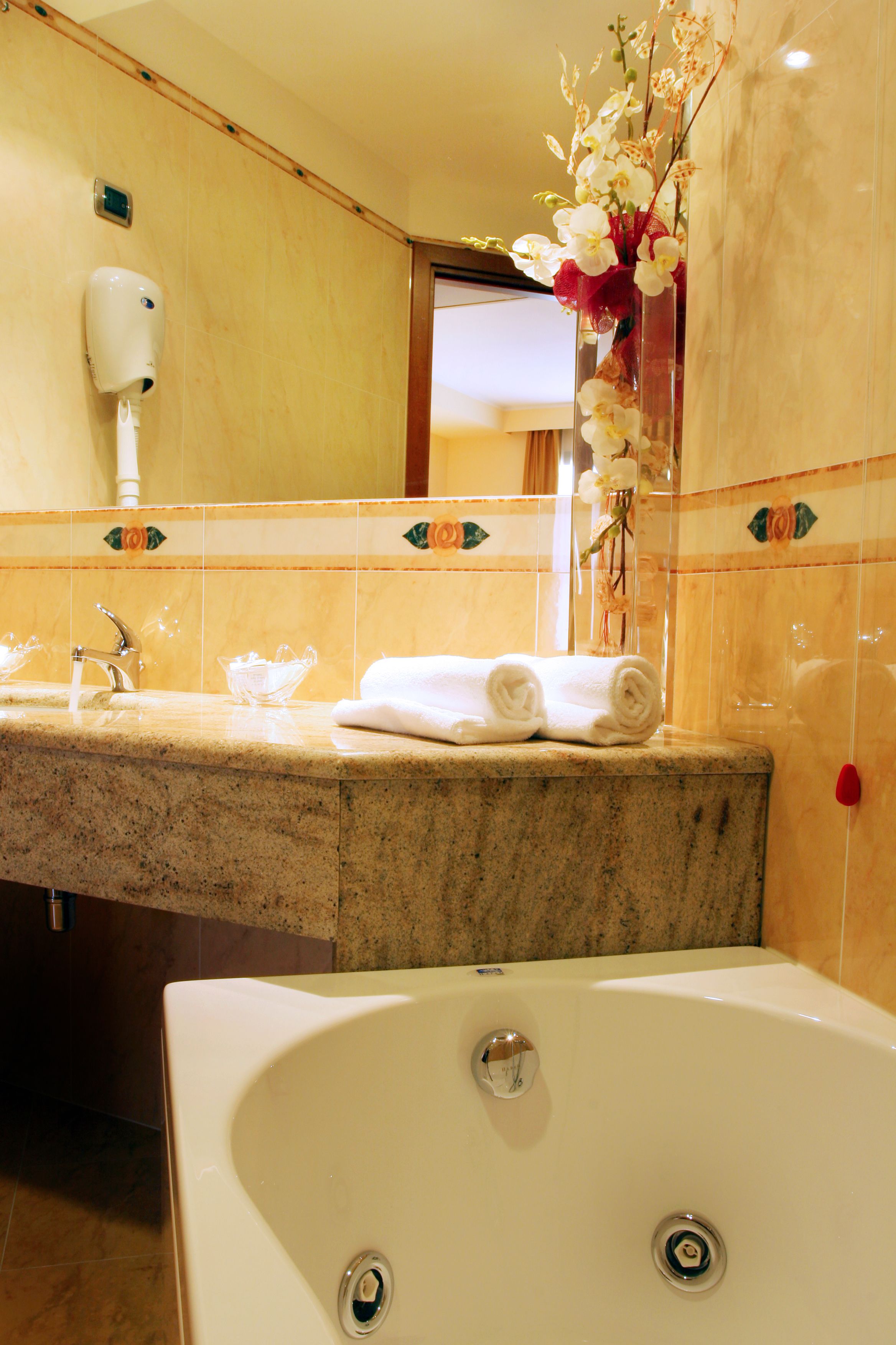 Ein Badezimmer mit Marmorwaschbecken, einer weißen Badewanne und einem Händetrockner.