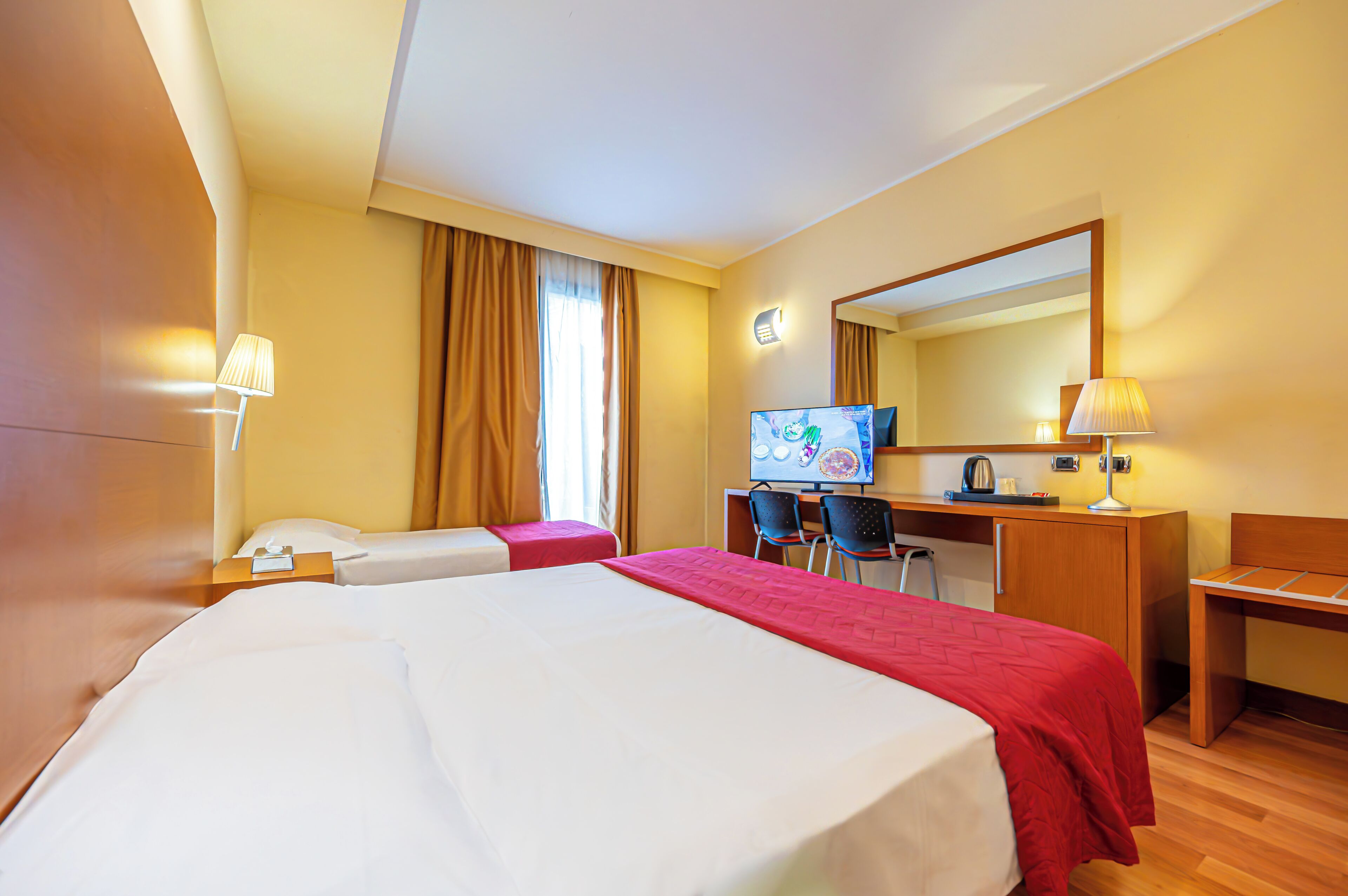 Une chambre d’hôtel avec un grand lit, un bureau avec une chaise, une télévision et un miroir.
