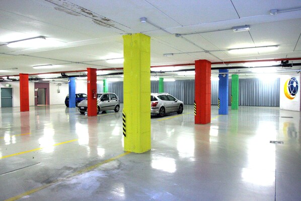 A parking garage with multiple cars parked, yellow and red pillars, and a fire extinguisher on the wall.