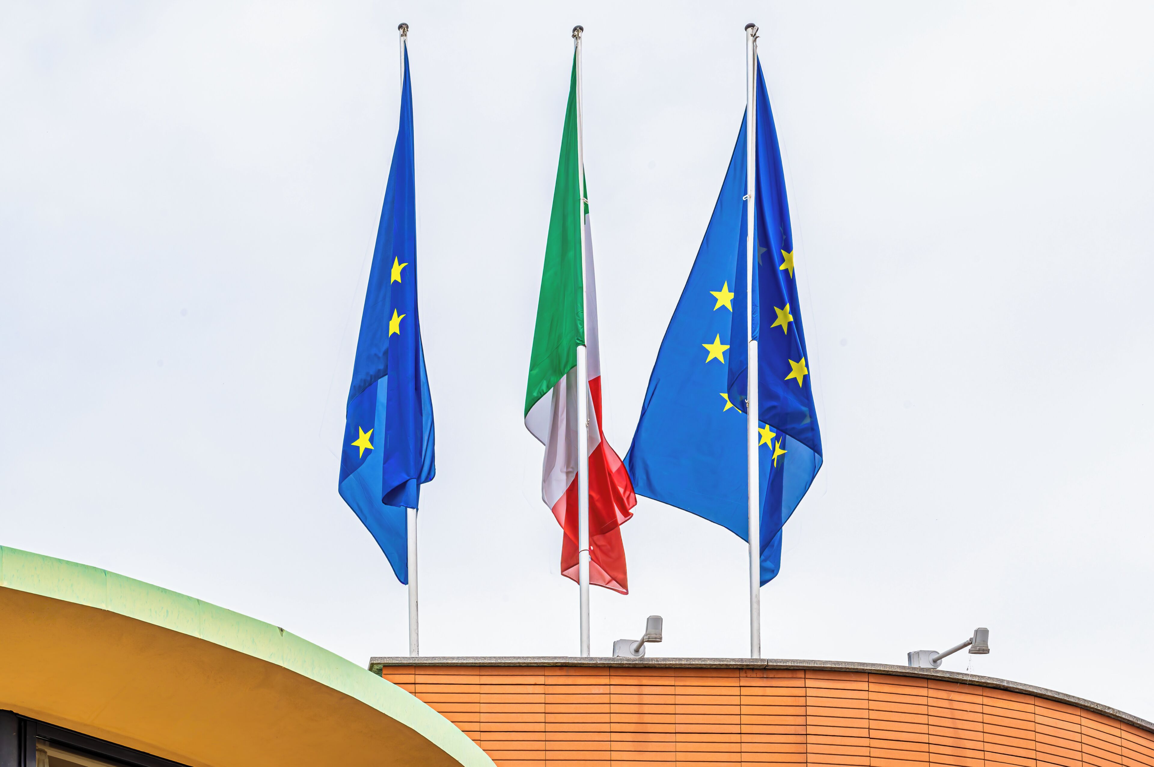 Three flags on a building's roof.