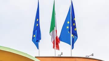 Three flags on a building's roof.