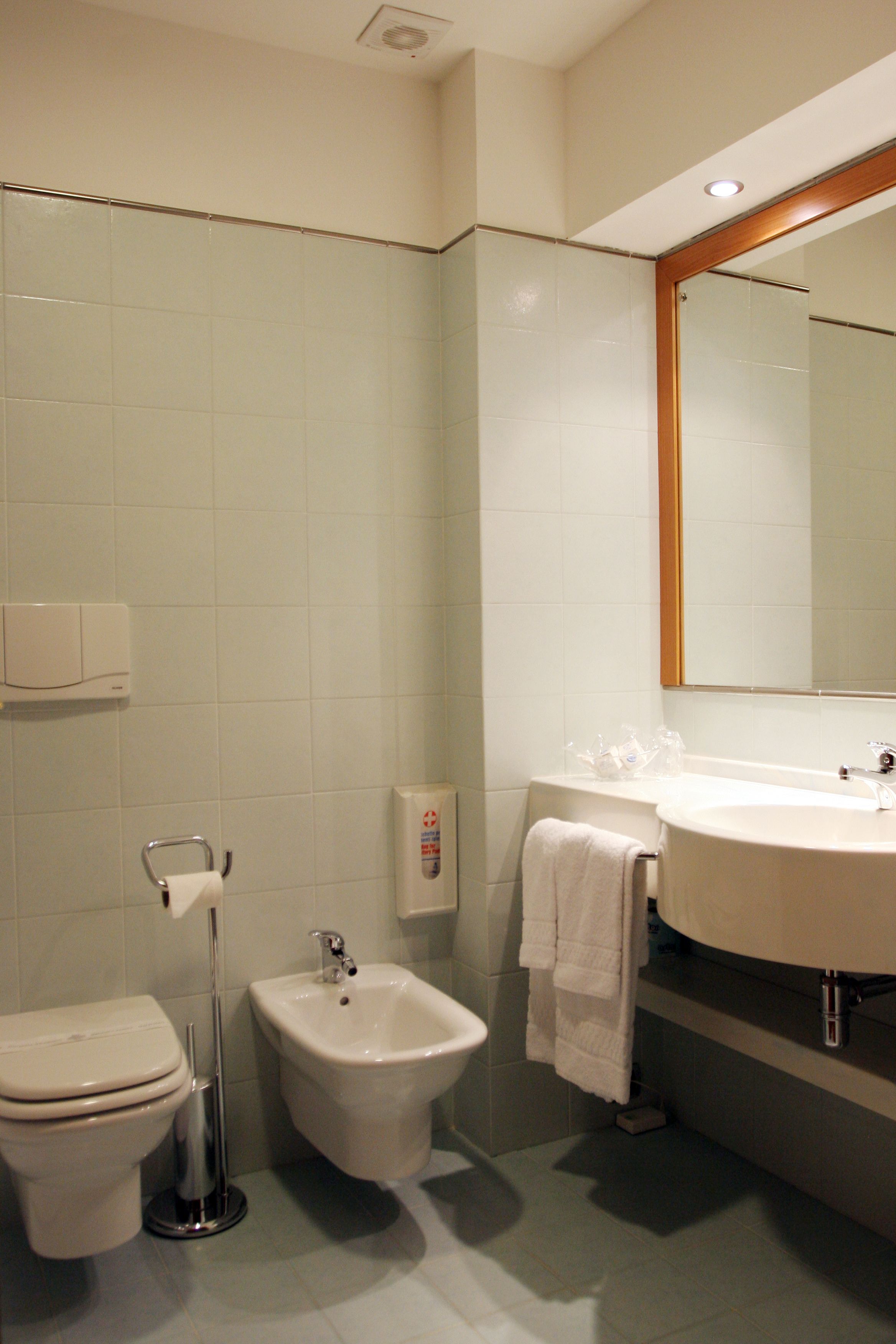 Un bagno con toilette, bidet, lavabo e specchio.