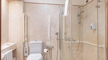 A bathroom with a toilet, bidet, and a glass-enclosed shower area.