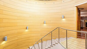 Un interior moderno con una cúpula de vidrio en el centro, una escalera curva y paneles de madera en las paredes.
