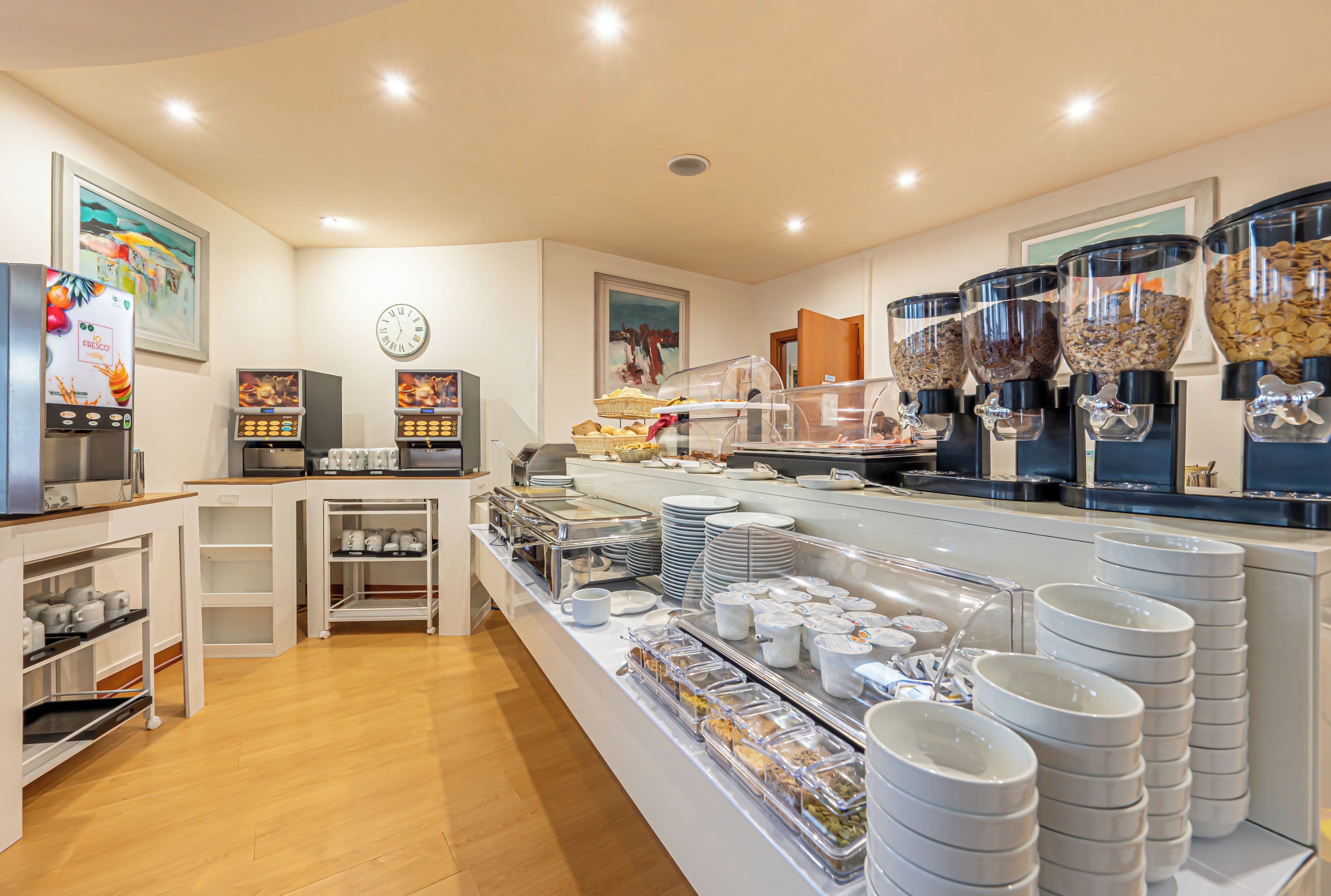 A buffet setup with food containers, plates, and a coffee machine.