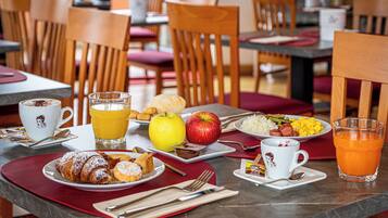 A breakfast setting with plates of food, drinks, and cutlery on a table.