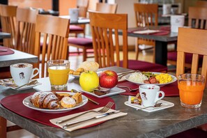 Et morgenbord med tallerkener mad, en kaffekop og et glas appelsinjuice.