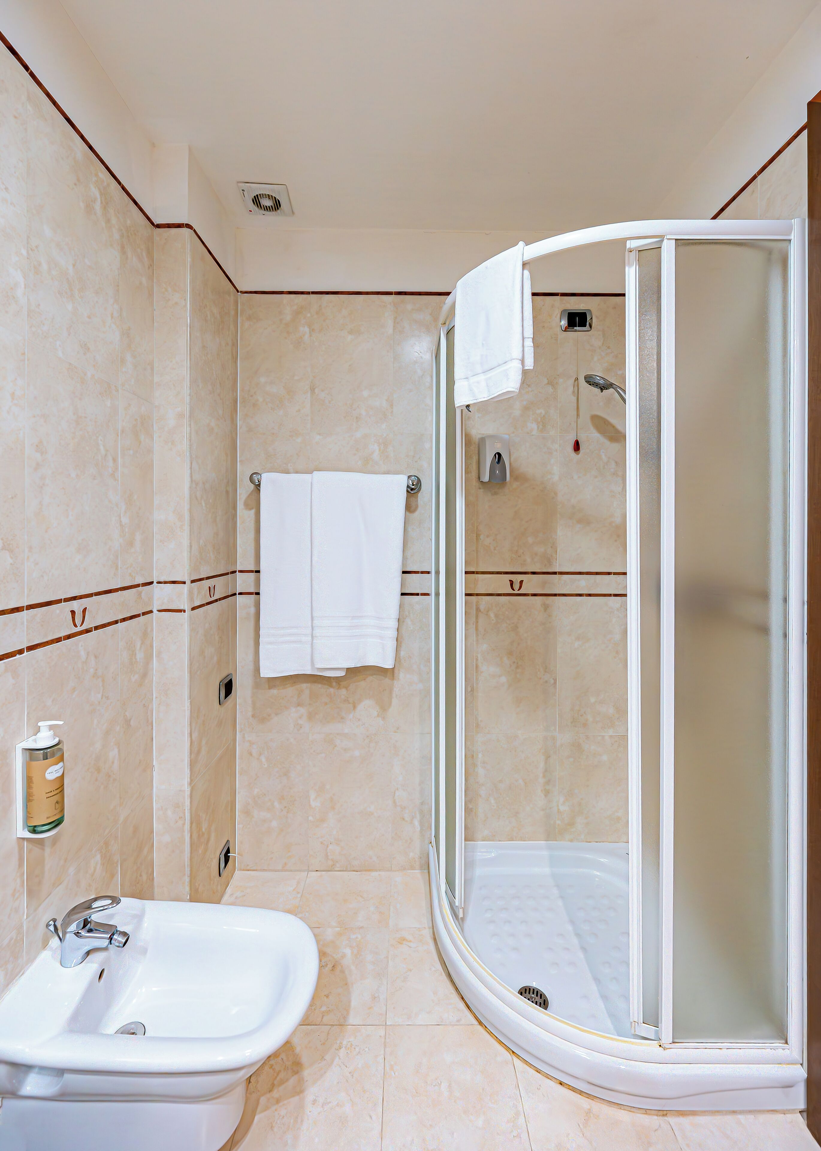 Une salle de bain avec une douche, un lavabo et un porte-serviettes.