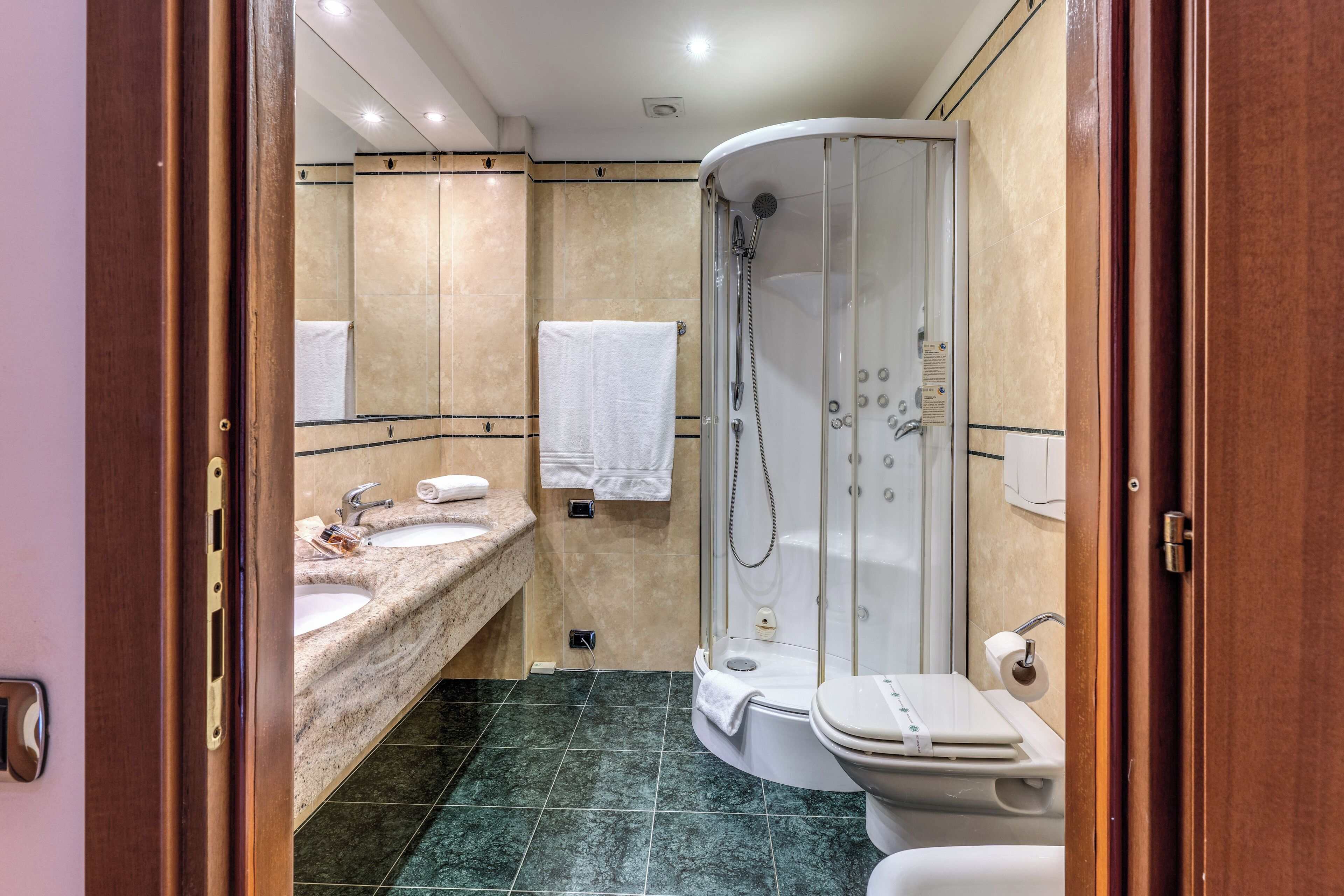 A bathroom with two sinks, a toilet, and a glass-enclosed shower.