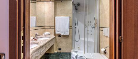 A bathroom with two sinks, a toilet, and a glass-enclosed shower.